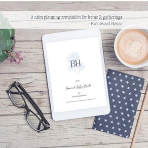 以下が含まれることがあります： 「BH」のイニシャルと「Home and Hosting Basics」のテキストが書かれた本の表紙が表示された白いタブレット。コーヒーカップ、メガネ、星柄のノートも写っています。