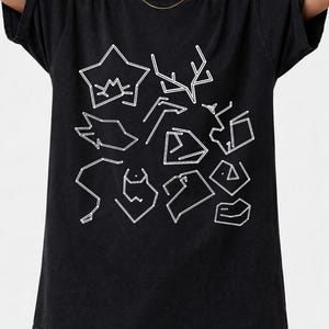 May include: Black t-shirt featuring a white line art design of various shapes and symbols. The design includes star-like figures, geometric shapes, and abstract forms. The shirt has a relaxed fit and short sleeves.