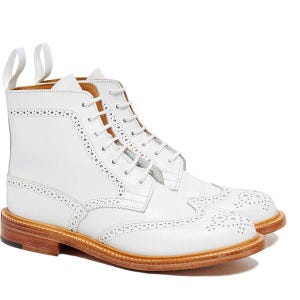 May include: White leather ankle boots with brogue detailing and a light brown sole. The boots feature a lace-up closure and pull tabs. A classic style, the boots are suitable for various occasions.