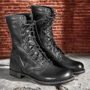 May include: A pair of black leather combat boots featuring a high-top design, rounded toes, and a lace-up front with metal eyelets. The boots have a sturdy construction with visible stitching along the soles and a smooth, matte leather finish.