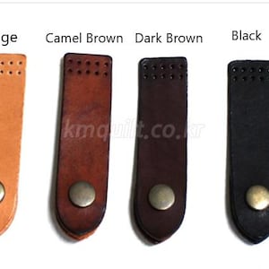 May include: Four leather bookmark straps in beige, camel brown, dark brown, and black. Each strap has a metal snap closure and a series of small holes at the top. The text "Beige", "Camel Brown", "Dark Brown", and "Black" are above each strap.