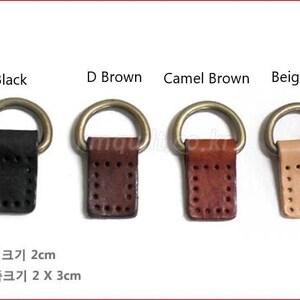 Puede incluir: Cuatro conectores de cuero con anilla en D en negro, marr&oacute;n oscuro, marr&oacute;n camel y beige. Cada uno tiene un anillo de metal dorado. Las leng&uuml;etas de cuero miden 2 cm de ancho y 3 cm de largo.