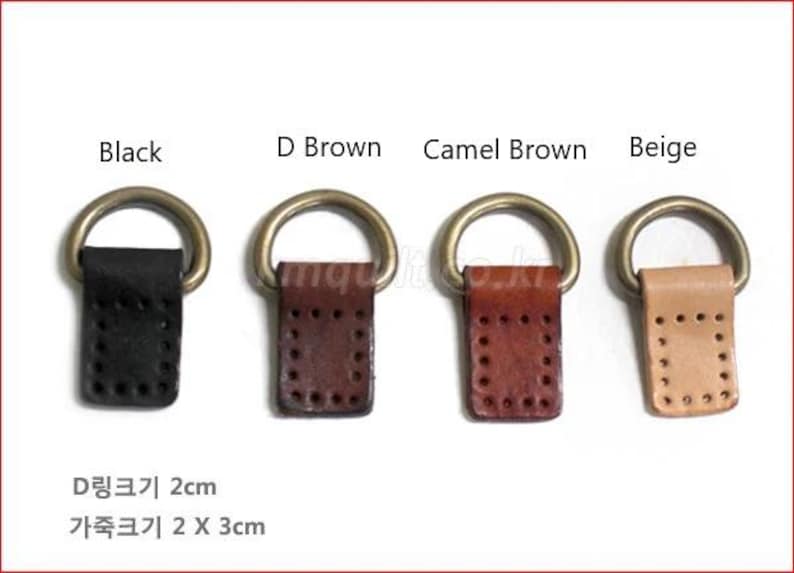 Puede incluir: Cuatro conectores de cuero con anilla en D en negro, marr&oacute;n oscuro, marr&oacute;n camel y beige. Cada uno tiene un anillo de metal dorado. Las leng&uuml;etas de cuero miden 2 cm de ancho y 3 cm de largo.