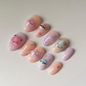 May include: A set of ten artificial nails with a variety of designs. The nails feature cartoon characters, a Poké Ball, and abstract patterns in pastel colors like pink, peach, and lavender. The nails are oval-shaped and have a glossy finish.