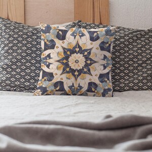 Könnte beinhalten: Dekorative Kissen auf einem Bett. Das mittlere Kissen zeigt ein Blumenmuster in Marineblau, Gelb und Creme. Die seitlichen Kissen haben ein geometrisches Muster in Marineblau und Weiß. Die Kissen liegen auf einer weißen Bettdecke.