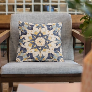 Puede incluir: Un sillón gris con un marco de madera oscura y un cojín de estampado azul y amarillo. El sillón está en una habitación con suelo de madera y una planta en un jarrón.