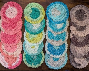 Peut inclure: Plusieurs dessous de verre faits à la main, crochetés, de différentes couleurs. Les dessous de verre sont disposés en piles verticales, présentant une gamme de teintes comprenant le rose, le vert, le bleu et le gris. Chaque dessous de verre a un design circulaire.