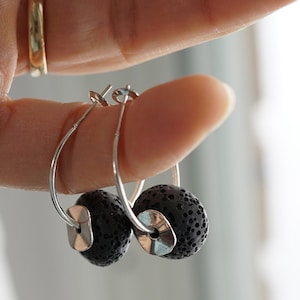 Op de afbeelding: Een paar zilveren creolen met zwarte lavastenen. De oorbellen zijn simpel en elegant en zouden een geweldig cadeau zijn voor elke gelegenheid.