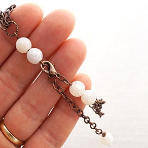 May include: A white agate beaded bracelet with a copper chain and clasp. The bracelet has a delicate, feminine look.