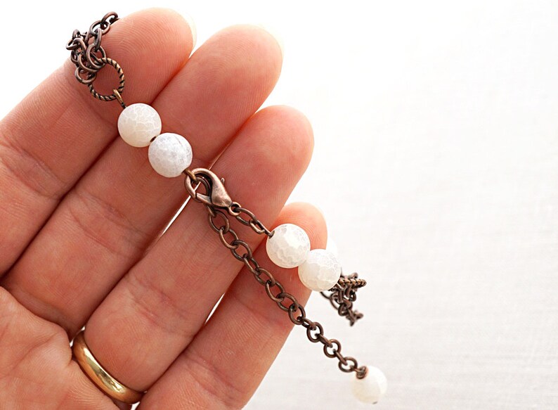 May include: A white agate beaded bracelet with a copper chain and clasp. The bracelet has a delicate, feminine look.