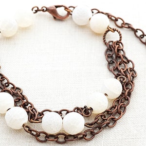 May include: A copper chain bracelet with white agate beads. The bracelet has a lobster clasp closure.