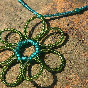 May include: A green beaded necklace with a flower pendant made of green and teal beads.