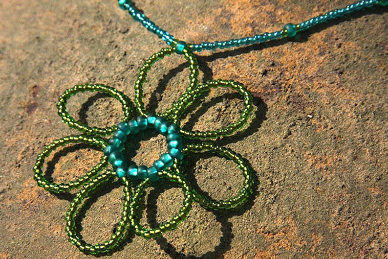 May include: A green beaded necklace with a flower pendant made of green and teal beads.