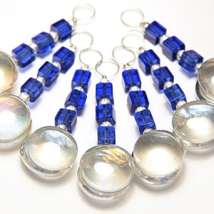 May include: A collection of six decorative keychains. Each keychain features a large, clear, iridescent glass orb, connected by a strand of blue, square beads and silver accents. The keychains have silver rings at the top.