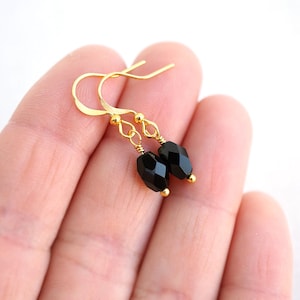 May include: Gold dangle earrings with black faceted glass beads.
