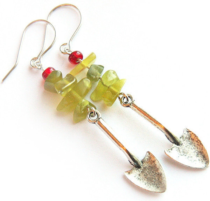 May include: Silver earrings with green and red gemstone beads and a silver shovel charm.