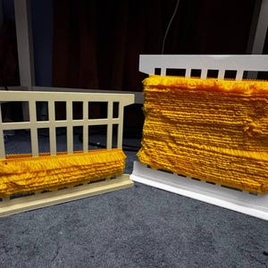 Puede incluir: Dos exhibidores decorativos de flecos. Uno es de color beige claro con flecos amarillos, y el otro es blanco con una gran pila de flecos amarillos. Los flecos están densamente empaquetados y parecen estar hechos de un material suave.