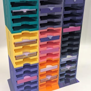 May include: A multi-colored organizer with 18 compartments for storing small items. The organizer is made of plastic and has a variety of colors, including teal, purple, yellow, pink, and orange.