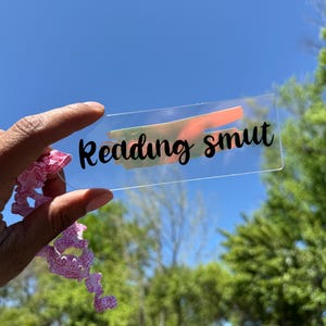 Marcapáginas de vinilo holográfico con pinceladas de acrílico transparente. Divertido regalo literario en cursiva para lectores, amigos y familiares románticos.