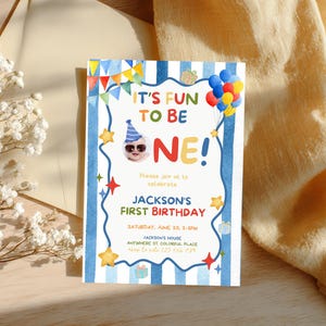 May include: A vibrant first birthday invitation with the words "IT'S FUN TO BE ONE!" in a whimsical font. The design includes a baby in sunglasses and a party hat, balloons, stars, and gift illustrations. The invitation is for Jackson's first birthday.