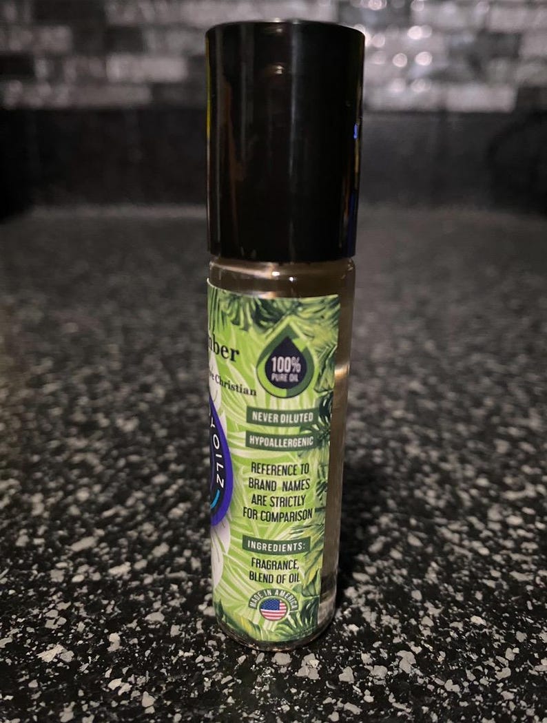 May include: A green and black roll-on bottle with a label that says "100% Pure Oil" and "Never Diluted Hypoallergenic". The label also includes the text "Reference to brand names are strictly for comparison" and "Ingredients: Fragrance Blend of Oil".