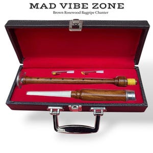 Puede incluir: Un juego de puntero de gaita de palisandro marrón en un estuche negro con interior rojo. El estuche está abierto, revelando el puntero, una boquilla y dos lengüetas. El texto "MAD VIBE ZONE" y "Brown Rosewood Bagpipe Chanter" están en la parte superior.