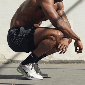 Może przedstawiać: Osoba w czarnych spodenkach sportowych i srebrnych butach do biegania z zielonym akcentem.