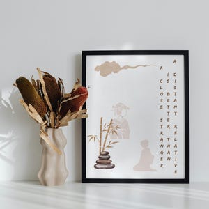 May include: A black framed print with a beige background and brown text that reads "A distant relative that I never knew." The print features a stylised illustration of a person in a traditional Japanese kimono standing next to a stack of stones and a bamboo plant.