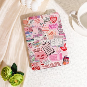 May include: A pink tablet case adorned with book-themed stickers. The stickers feature phrases such as "Book Lover," "Bookish Girlie," and "Hello I'm Reading Go Away." Other stickers depict books, coffee cups, and a ghost reading a book.