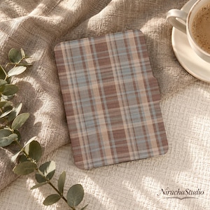 May include: A rectangular e-reader case featuring a brown, beige, and light blue plaid pattern. The case has a smooth, flat surface with rounded corners and a small cutout notch on the right side, displaying a consistent grid of intersecting lines.