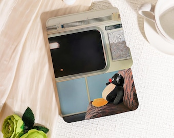 May include: A phone case featuring a cartoon penguin wearing headphones, seated inside a train car. The case has a light blue and beige color scheme, with a map detail. The penguin has a red nose and yellow feet.