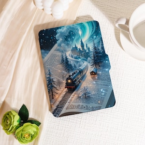 Può includere: Una copertina di libro a tema fantasy con un treno che viaggia sui binari verso un castello, ambientata in un paesaggio innevato con un'aurora boreale. La copertina è aperta, rivelando pagine stampate.