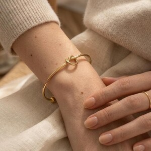 Peut inclure: Une tasse en céramique blanche avec une anse noire et le texte "But First, Coffee" en gras noir. La tasse est posée sur un fond flou, suggérant un cadre chaleureux.