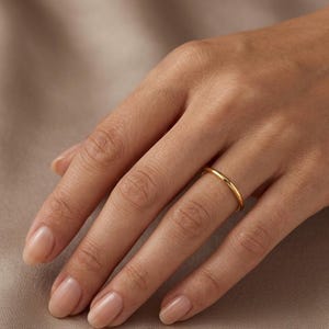 Peut inclure: Une fine bague dorée est portée au doigt. La bague a un design simple et minimaliste, avec une surface lisse et polie. Ce bijou classique convient au quotidien ou aux occasions spéciales.