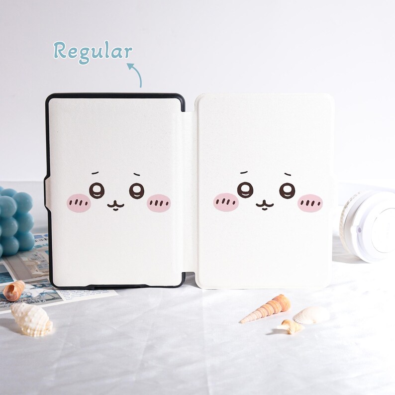 Pu&ograve; includere: Custodia bianca per tablet con un design a forma di viso di cartone animato. La custodia &egrave; aperta, rivelando l'interno e il design sul davanti. Il design presenta due grandi occhi, guance rosee e una bocca piccola. La parola "Regular" &egrave; scritta sopra la custodia.