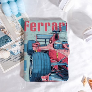 Può includere: Un'illustrazione di una Ferrari di Formula 1 rossa e blu su una custodia. La custodia presenta la parola "Ferrari" in lettere rosse. Lo sfondo è azzurro con dettagli architettonici.