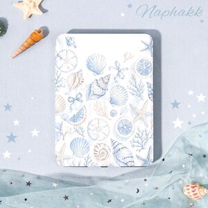Könnte beinhalten: Eine rechteckige E-Reader-Hülle mit weißem Hintergrund und einem wiederkehrenden Aquarellmuster aus hellblauen Muscheln, Seesternen, Korallen und Zitrusfrüchten. Das Wort Naphakk ist oben rechts in einer Schreibschrift gedruckt.