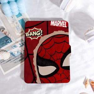 May include: A red and black Marvel Spider-Man tablet case. The case features a comic book style design with the word "BANG!" in a speech bubble and the Marvel logo. The Spider-Man mask is partially visible.