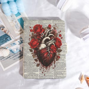 May include: A rectangular case with a detailed illustration of a human heart and red roses. The heart is in red and white, with anatomical details. The background is a vintage dictionary page, with text in black.