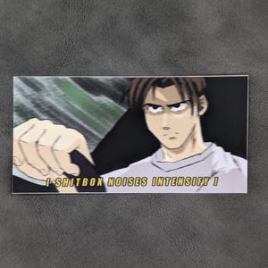 May include: Rectangular sticker featuring an anime-style illustration of a man with brown hair and a determined expression. The sticker has the text "I-SHITBOX NOISES INTENSIFY!" in a yellow font.