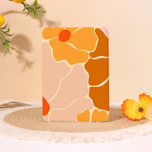 Peut inclure: Une coque de tablette rectangulaire présentant un motif graphique composé de grandes formes organiques abstraites dans des tons orange, orange brûlé, jaune et rose pâle, séparées par de fines lignes claires sur toute la surface avant.