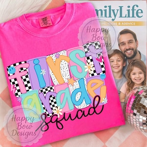 Könnte beinhalten: Ein leuchtend pinkfarbenes T-Shirt mit dem Schriftzug "First Grade Squad" in einem farbenfrohen Retro-Design. Das Design umfasst Schachbrettmuster, Sterne und Blumen. Das Shirt ist von der Marke Comfort Colors.