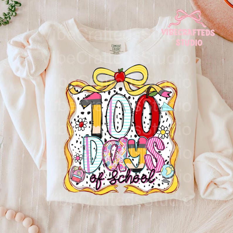 Puede incluir: Sudadera de manga larga color crema con un gr&aacute;fico colorido que celebra "100 d&iacute;as de escuela". El dise&ntilde;o incluye los n&uacute;meros "100", l&aacute;pices, manzanas, flores y un globo terr&aacute;queo, todo dentro de un marco decorativo. El texto est&aacute; en una fuente multicolor juguetona.