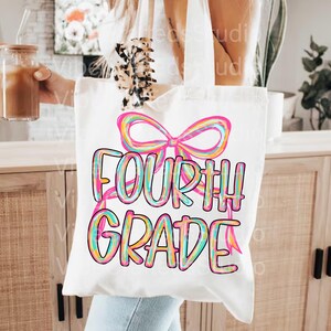 Pode incluir: Bolsa tote de lona branca com as palavras "FOURTH GRADE" em letras coloridas. Um grande la&ccedil;o rosa est&aacute; acima do texto. A bolsa tem duas al&ccedil;as brancas.