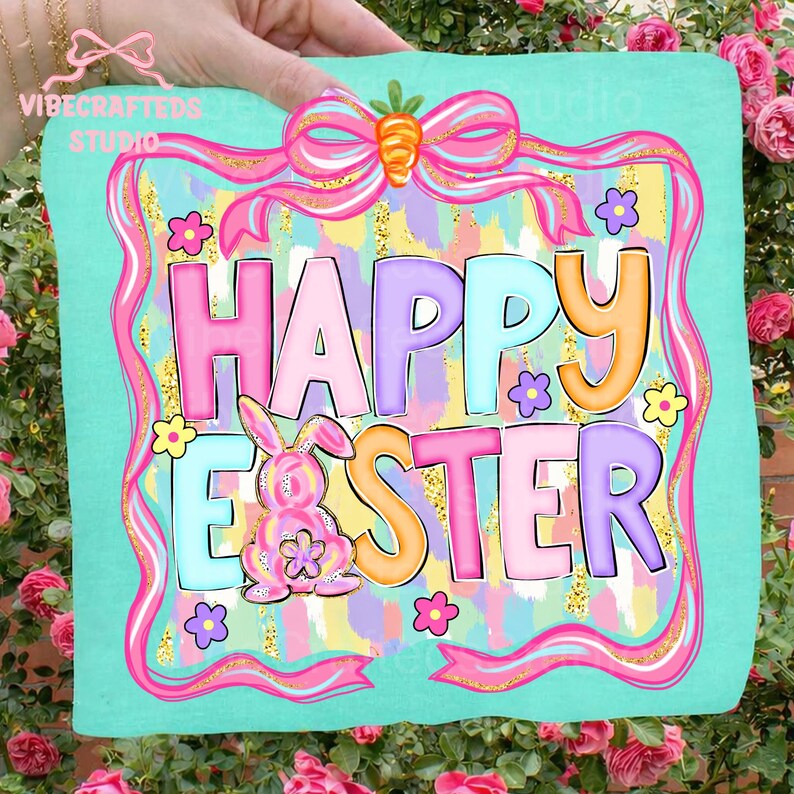 May include: A turquoise square with the words "HAPPY EASTER" in colorful bubble letters. A pink bunny and flowers decorate the design, which is framed by a pink ribbon and bow with a carrot accent. The words "VIBECRAFTED STUDIO" are in the upper left corner.