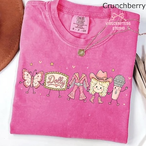 May include: A pink short-sleeve t-shirt featuring a graphic print of a butterfly, a marquee sign with the text Dolly, a fringed outfit, a blonde character wearing a cowboy hat and boots, and a microphone, all connected by thin black lines.