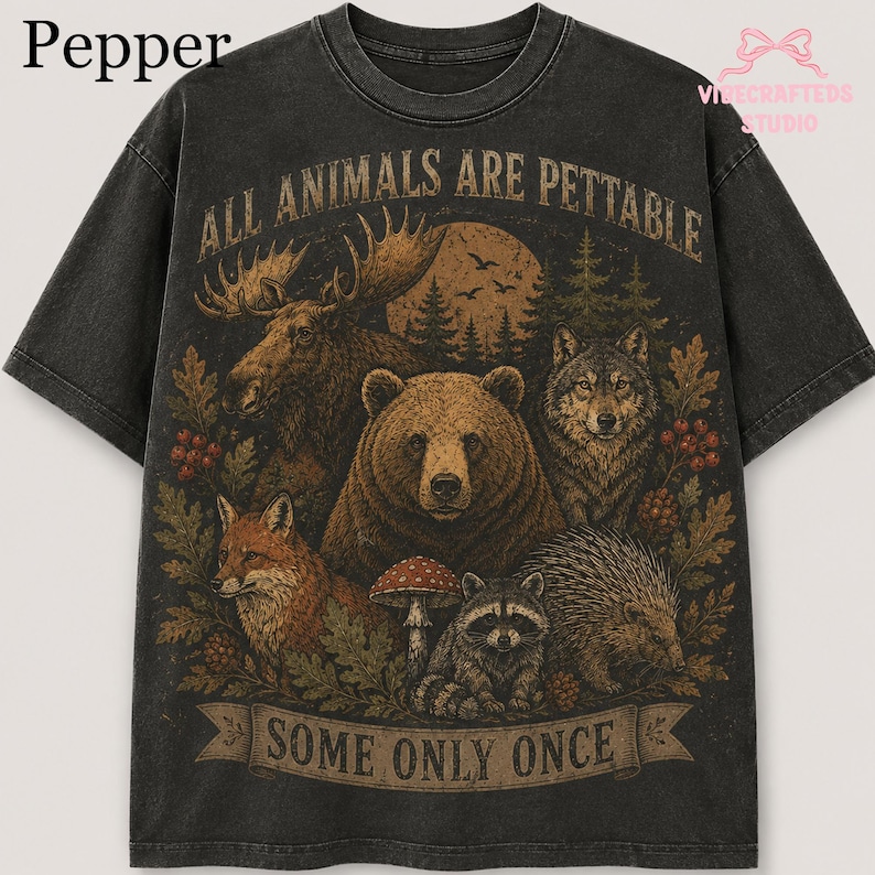 Pu&ograve; includere: Una t-shirt grigio antracite a maniche corte con una stampa grafica raffigurante un alce, un orso, un lupo, una volpe, un procione e un istrice in una foresta. Il testo recita ALL ANIMALS ARE PETTABLE sopra e SOME ONLY ONCE sotto.