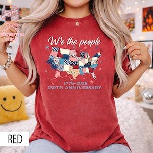 May include: A red t-shirt with a patchwork map of the United States. The words "We the people" are above the map, with "1776-2026 250TH ANNIVERSARY" below. The shirt is a casual style.
