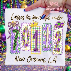 Może przedstawiać: Biała koszulka z napisem "Laissez les bon temps rouler" i "New Orleans, LA". Projekt przedstawia liczby "70112" w kolorze fioletowym, zielonym i żółtym, z akcentami w stylu Mardi Gras.