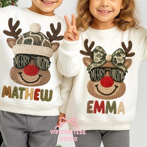May include: Two off-white sweatshirts featuring reindeer designs. Each reindeer has brown antlers, sunglasses with "Merry Christmas" text, and a red nose. One sweatshirt says "Mathew" and the other says "Emma" in colourful letters.